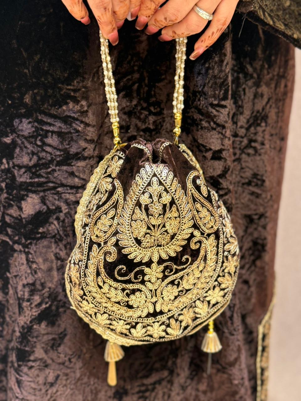 Royal velvet outfit with intricate golden embroidery and handcrafted potli bag